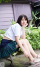 A young woman sitting on a wooden bench in a school uniform.